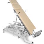 Stół do masażu z regulowanym oparciem i podnóżkiem, na metalowej konstrukcji z kółkami i mechanizmami regulacji.