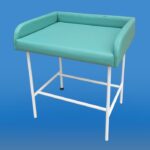 Stół do przewijania niemowląt z miękką, zieloną nakładką i białą metalową ramą na czterech nogach.