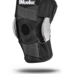 Ochraniacz na kolano marki Mueller z czarną i szarą konstrukcją, z elastycznymi paskami i otworem na rzep.