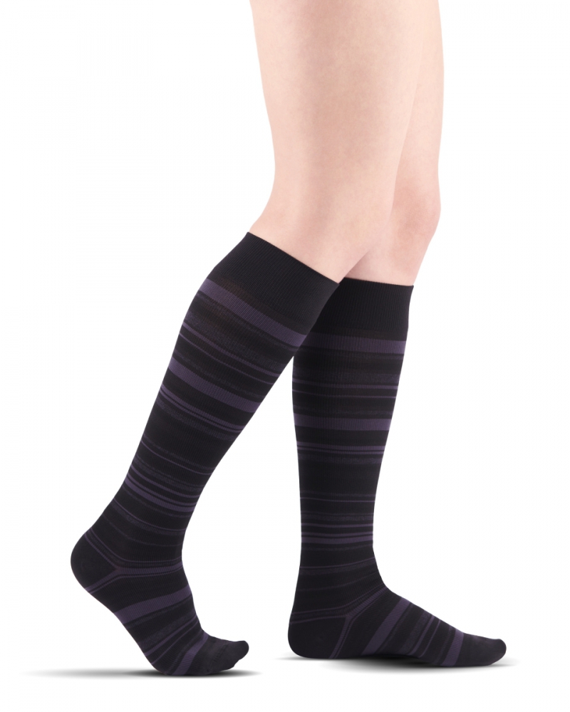 Długie skarpety w czerni i fioletowe paski na nogach osoby stojącej.