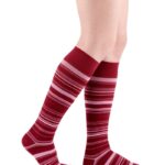 Cienkie, długie skarpety w czerwono-różowe paski na nogach osoby.