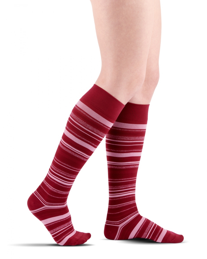 Cienkie, długie skarpety w czerwono-różowe paski na nogach osoby.