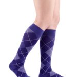 Nogi mężczyzny w niebieskich skarpetach z szarym wzorem w romby.