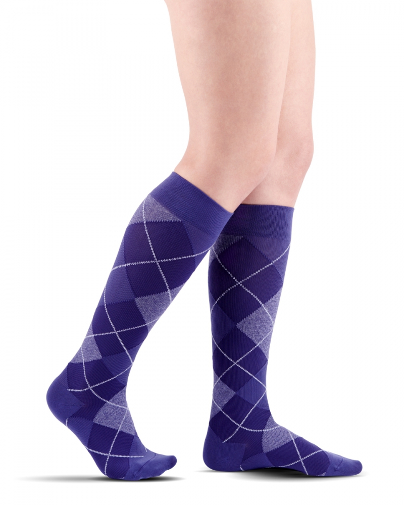 Nogi mężczyzny w niebieskich skarpetach z szarym wzorem w romby.