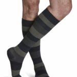 Para męskich nóg w czarno-szarych pasiastych skarpetach, z widoczną owłosioną skórą i zgiętymi kolanami.