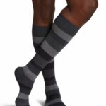 Para męskich nóg w czarno-szarych pasiastych skarpetach, z ciemną skórą, na białym tle.