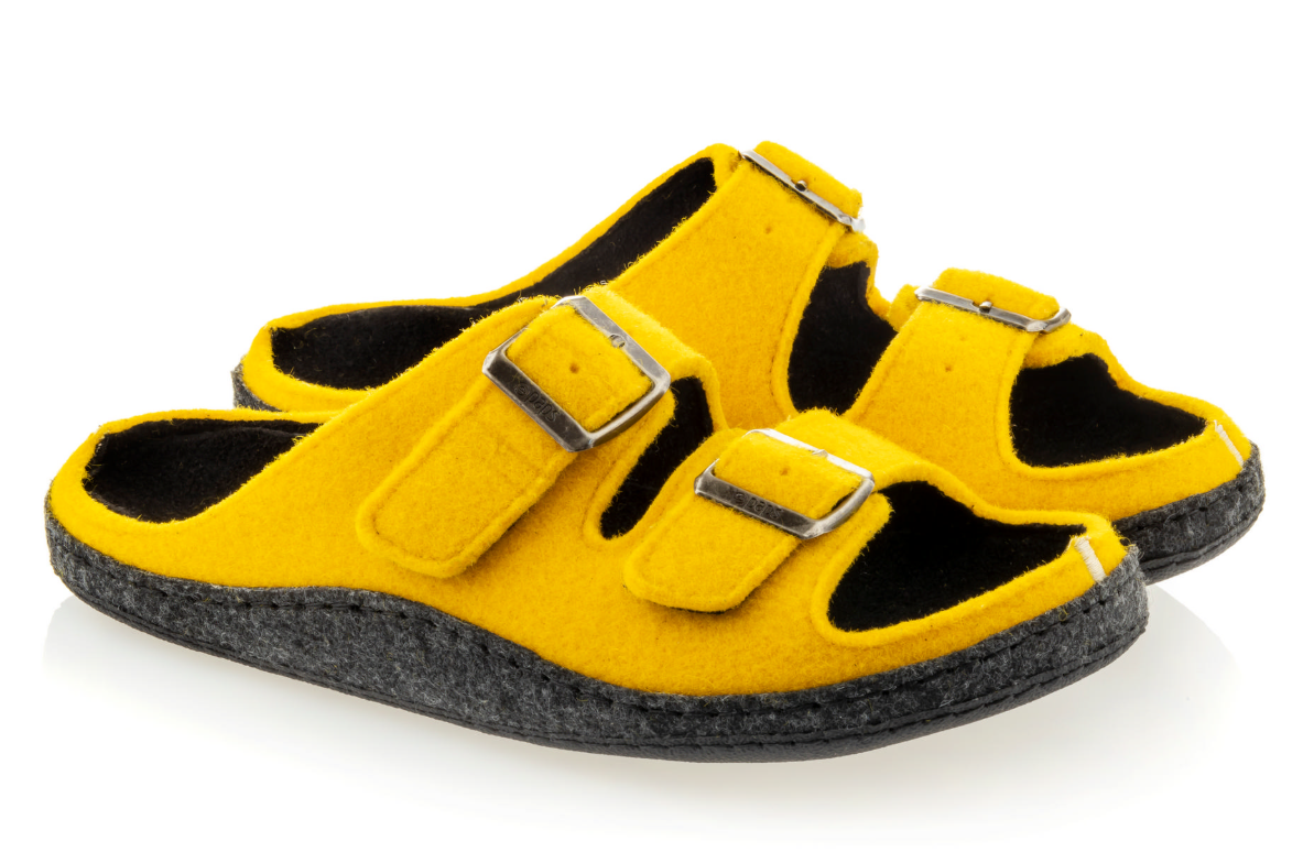 Żółte kapcie z czarnymi wstawkami, dwoma paskami z metalowymi klamrami i miękką podeszwą.