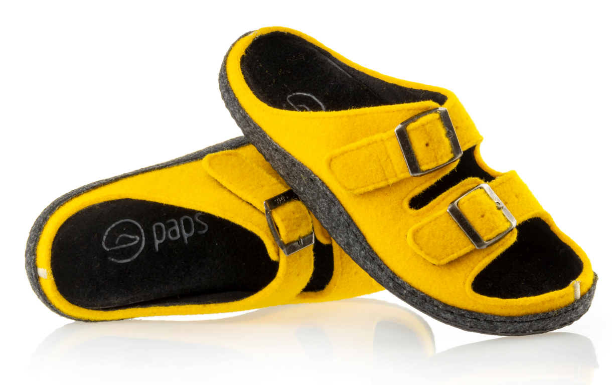 Żółte kapcie z dwoma regulowanymi paskami i czarnymi wstawkami, miękkie, na płaskiej podeszwie.