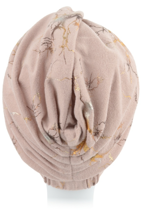 Beżowa czapka z nadrukiem gałęzi i złotymi akcentami, ułożona na białej głowie.
