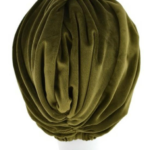 Zielony turban z miękkiego, plisowanego materiału na białej głowie.