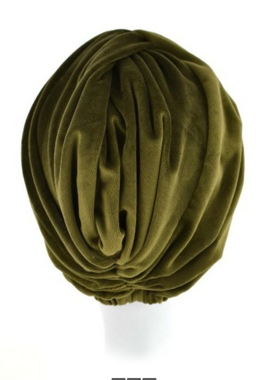 Zielony turban z miękkiego, plisowanego materiału na białej głowie.