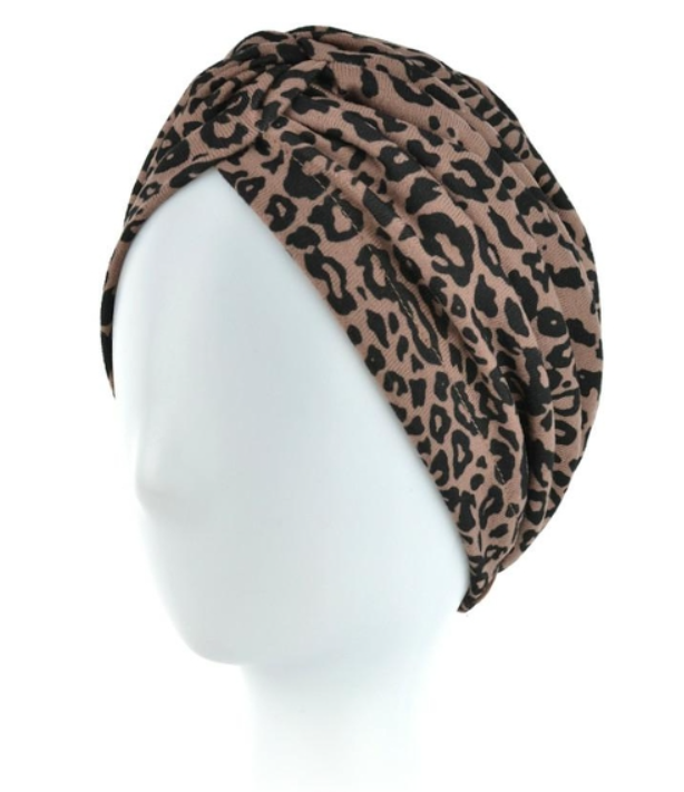 Turban w brązowo-czarne leopardie na białej głowie.