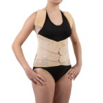 Kobieta nosi ortopedyczny pas i kamizelkę wspierającą plecy, ubrana w czarny top i majtki, z rękami na biodrach.