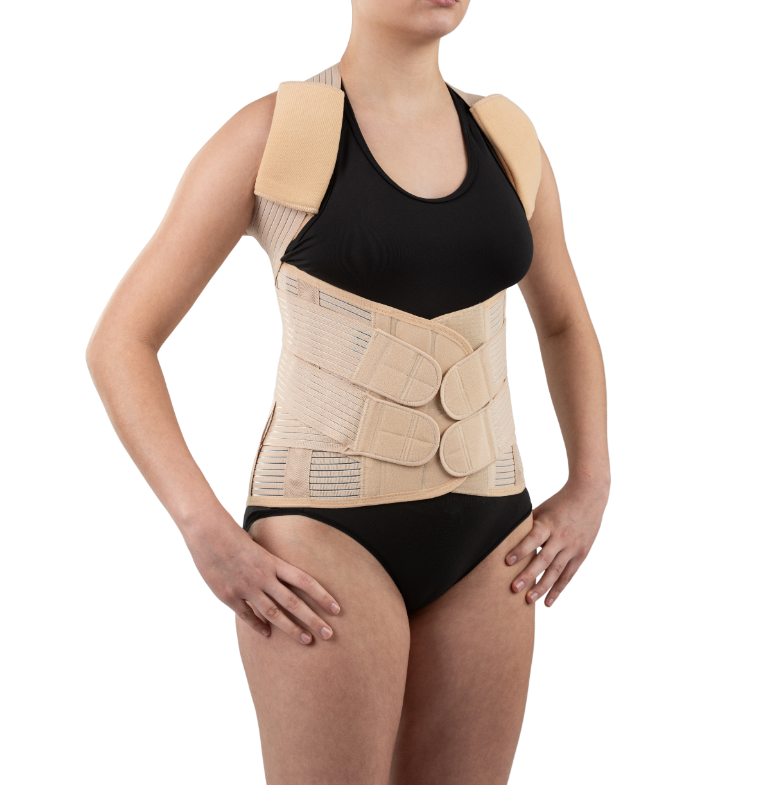 Kobieta nosi ortopedyczny pas i kamizelkę wspierającą plecy, ubrana w czarny top i majtki, z rękami na biodrach.