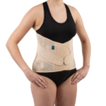 Osoba nosząca ortopedyczny pas stabilizujący na talii, ubrana w czarny top i majtki, stojąca z rękami na biodrach.