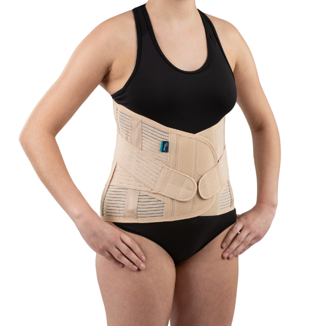 Osoba nosząca ortopedyczny pas stabilizujący na talii, ubrana w czarny top i majtki, stojąca z rękami na biodrach.
