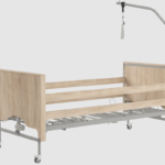 Szpitalny łóżko z drewnianymi panelami, metalową ramą, kółkami i wysięgnikiem na kroplówkę.