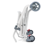 Składany, lekki wózek inwalidzki z białą ramą, małymi kołami i czerwonymi hamulcami, złożony na białym tle.