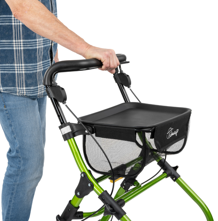 Osoba trzymająca się uchwytu składanej, zielonej laski z koszykiem na zakupy, na białym tle.