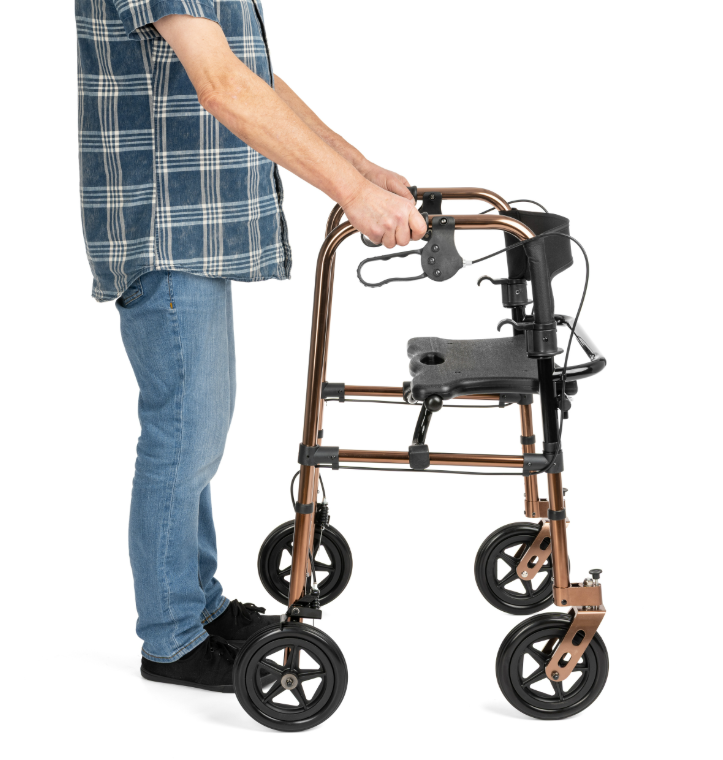 Osoba trzymająca się poręczy lekkiego chodzika z czterema kółkami, ubrana w niebieską koszulę i jeansy.