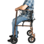 Osoba siedząca na lekkim, składanym wózku inwalidzkim z metalową ramą i czterema kołami, ubrana w koszulę w kratę i j