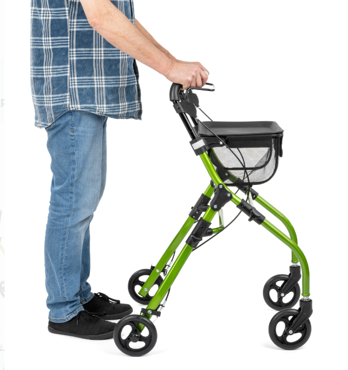 Osoba korzystająca z zielonego chodzika inwalidzkiego z koszykiem, trzymająca uchwyt, na białym tle.