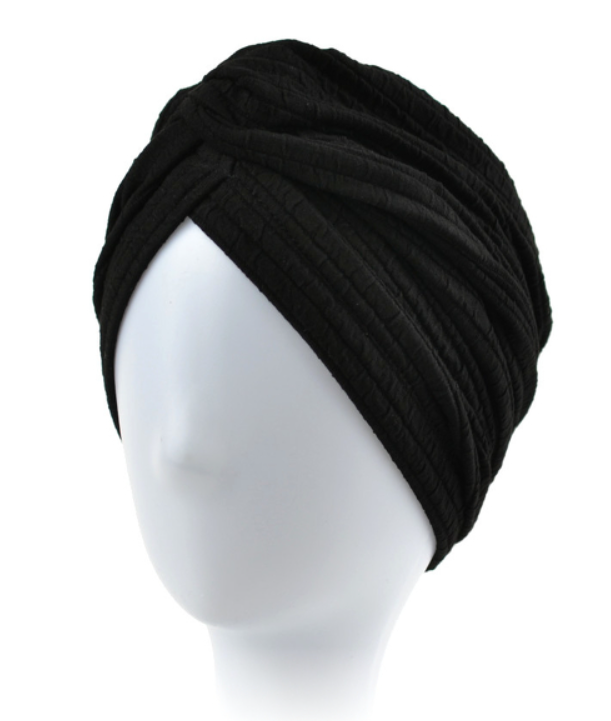 Czarna, miękka czapka typu turban na głowie na białej głowie manekina.