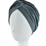 Szara turban na głowie na białej manekinie, owinięty wokół głowy z zakładkami i marszczeniami.