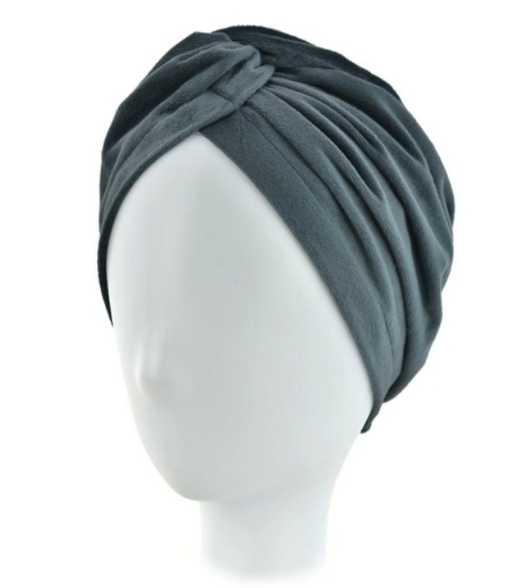 Szara turban na głowie na białej manekinie, owinięty wokół głowy z zakładkami i marszczeniami.