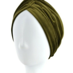 Zielona, miękka opaska na głowę lub turban na białej głowie manekina.