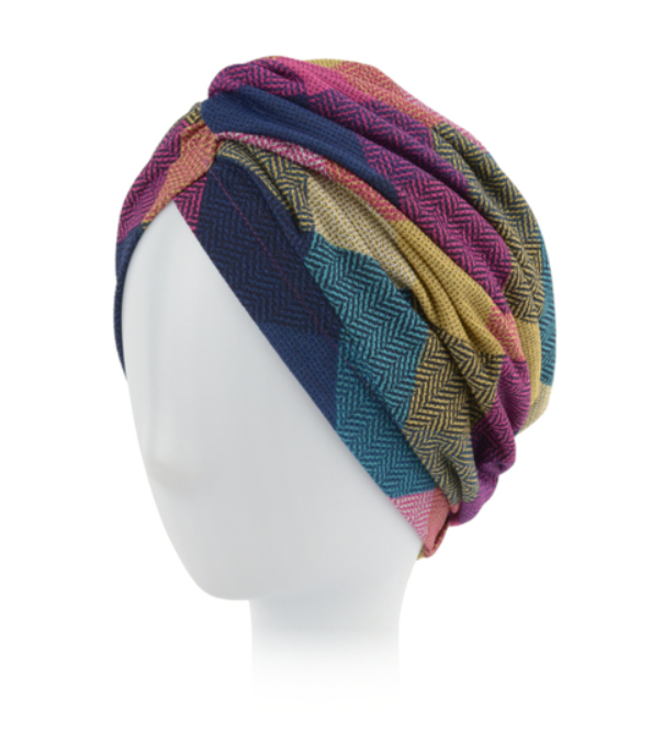 Kolorowa, wielowarstwowa chusta z wzorzystej tkaniny na białej głowie manekina.