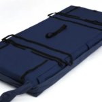 Niebieski materac ratunkowy z czarnymi pasami i uchwytami, rozłożony na białym tle.