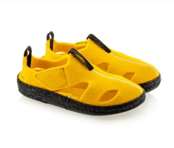 Żółte kapcie z czarnymi elementami i czarną podeszwą, wykonane z miękkiego materiału, z pętelkami na pięcie.