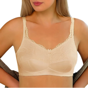 Kobieta w beżowym biustonoszu z koronkowymi ramiączkami, trzymająca się za talię, z częściowo odsłoniętą ramionami.