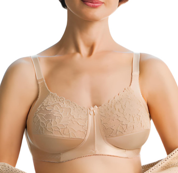 Kobieta w beżowym biustonoszu z koronkowymi zdobieniami i cienkimi ramiączkami, uśmiechnięta, z widocznym dekoltem.