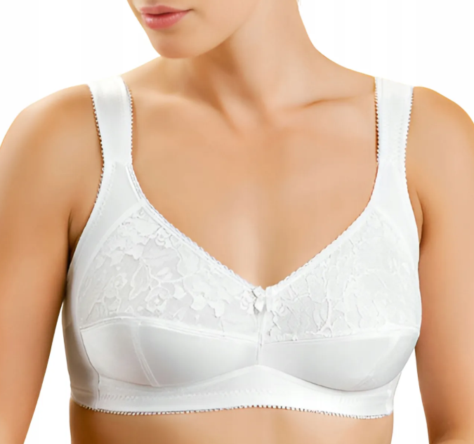 Kobieta w białym biustonoszu z koronkowym wzorem i szerokimi ramiączkami, widoczna od ramion do połowy torsu.