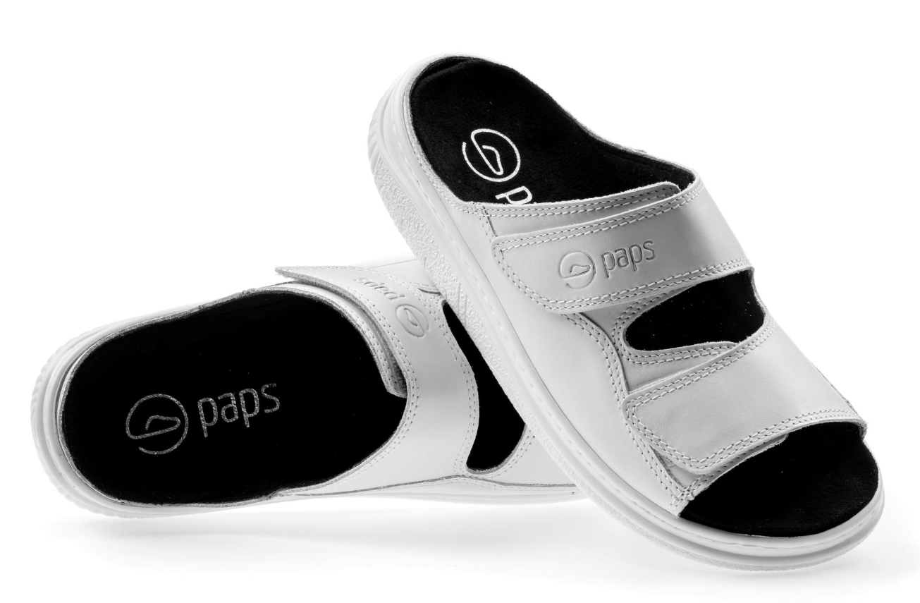 Białe kapcie z czarnym wnętrzem i logo paps na pasku, ustawione na białym tle.