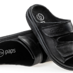 Czarne, otwarte sandały na rzepy z logo saps na wkładce i paskami z przetarciami, ustawione na białym tle.