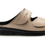 Kapcie na miękkiej podeszwie z dwoma regulowanymi rzepami, w kolorze beżowym, z czarnym wkładem i podeszwą.