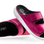 Różowe kapcie z czarnym wnętrzem i białą podeszwą, z dwoma szerokimi rzepami na wierzchu.